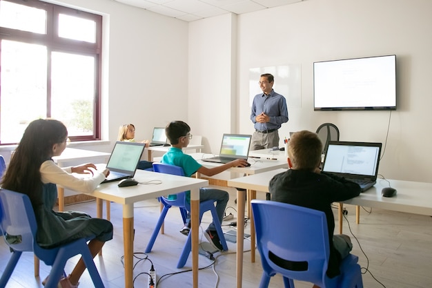 Foto gratuita profesor seguro explicando la lección a los alumnos