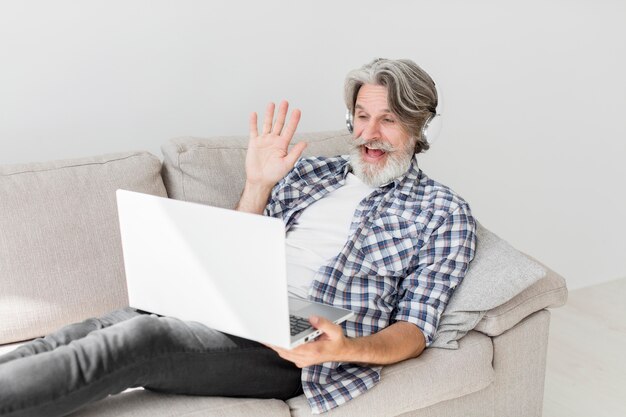 Profesor en el sofá saludando a la computadora portátil