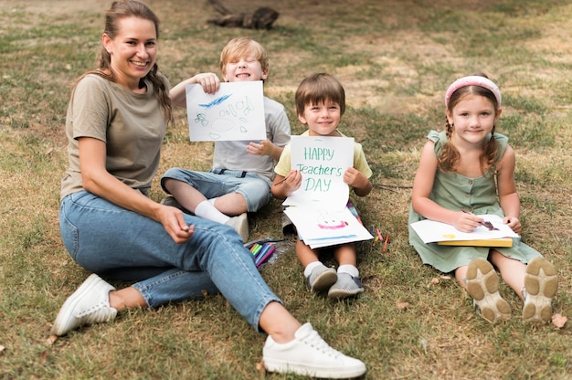 Profesor sonriente de alto ángulo y niños al aire libre