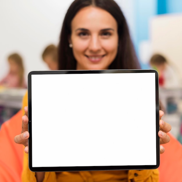 Profesor sonriente sosteniendo una tableta de pantalla vacía