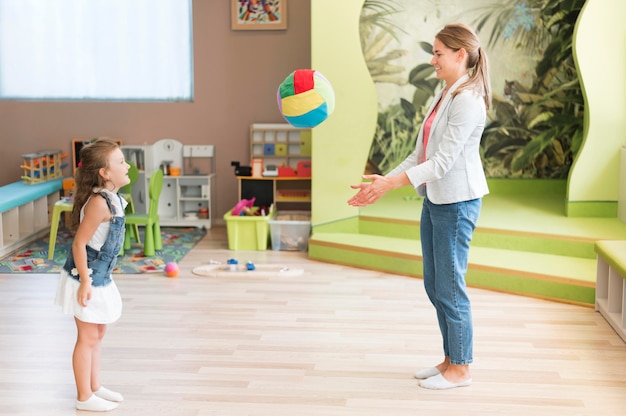 Profesor de tiro completo y niña jugando con pelota