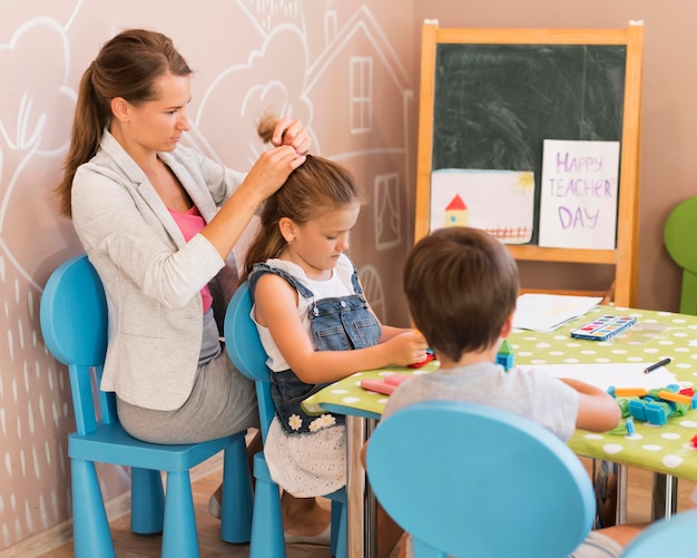 Profesor de tiro medio atando el cabello de la niña