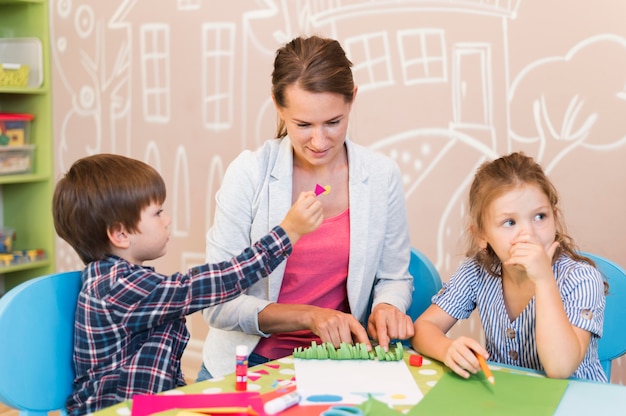 Profesor de tiro medio ayudando a los niños