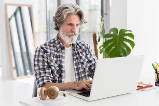 Profesor de tiro medio en el escritorio usando una computadora portátil