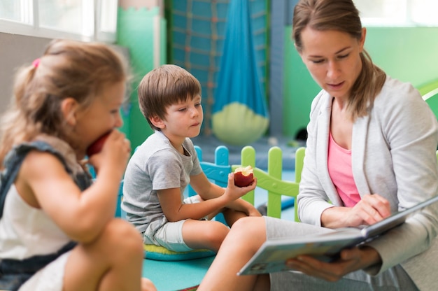 Profesor de tiro medio leyendo a niños