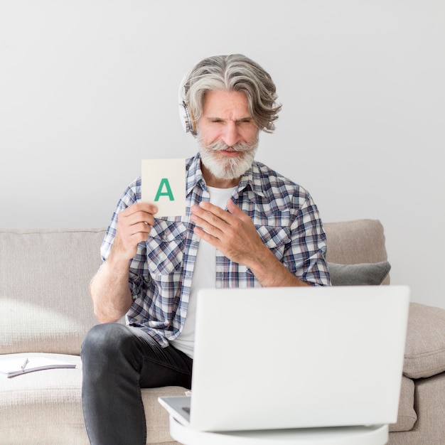 Profesor de tiro medio mostrando tarjeta de carta en la computadora portátil