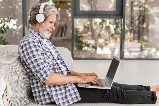 Profesor de tiro medio usando laptop sentado en el piso