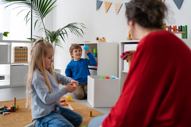 Foto gratuita profesor de tiro medio viendo a los niños aprender