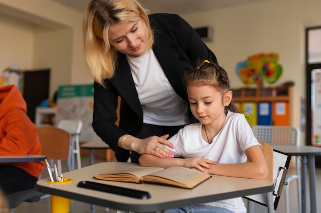 Foto gratuita profesor de vista frontal ayudando a niño