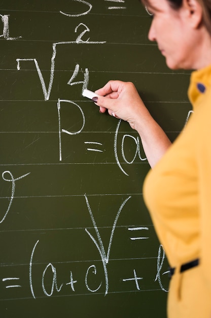 Profesor de vista lateral escribiendo en la pizarra