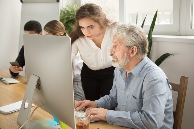 Profesora ejecutiva, trabajadora de oficina de alto rango que ayuda a explicar el trabajo de la computadora
