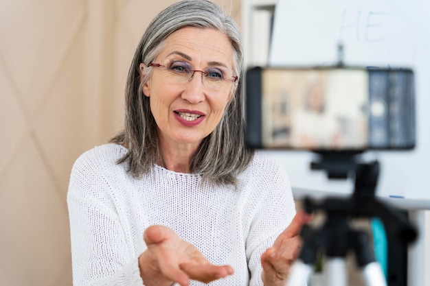 Profesora de inglés sonriente haciendo lecciones en línea en su teléfono inteligente