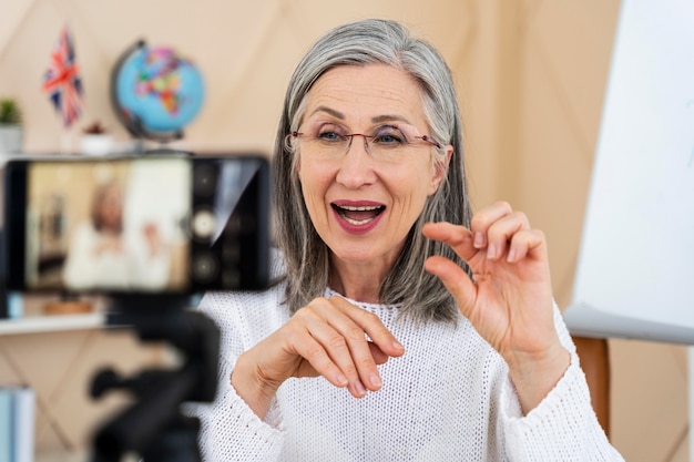 Profesora de inglés sonriente haciendo lecciones en línea en su teléfono inteligente