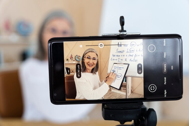 Foto gratuito profesora de inglés sonriente haciendo lecciones en línea en su teléfono inteligente