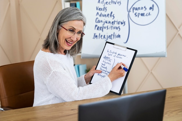 Foto gratuita profesora de inglés sonriente haciendo lecciones en línea