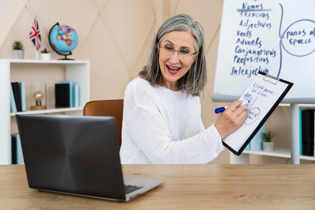 Foto gratuita profesora de inglés sonriente haciendo lecciones en línea