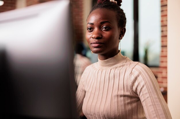 Programador afroamericano haciendo una lluvia de ideas para escribir código y crear una nueva interfaz en la sala de datos. Ingeniero de sistemas programando la base de datos del servidor en una ocupada agencia de desarrollo de inteligencia artificial.