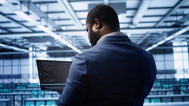 Programador en el centro de datos haciendo el chequeo de mantenimiento anual usando una computadora portátil