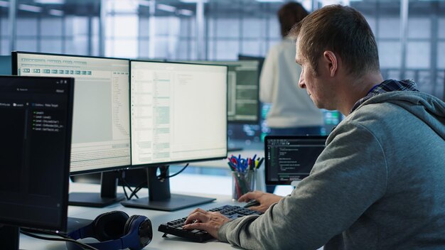 Programador de TI llegando al trabajo en el centro de datos sentado en el escritorio de la PC