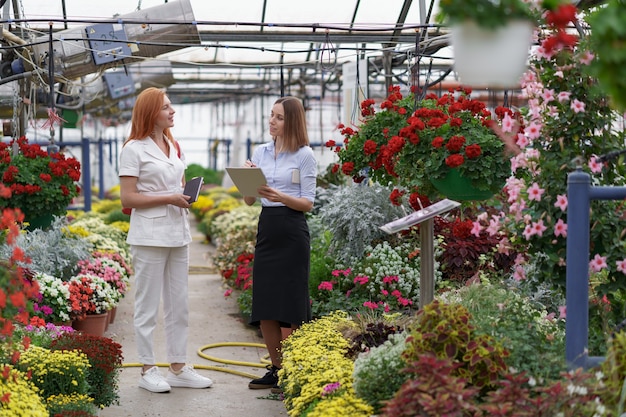 Propietario de invernadero presentando opciones de flores a un posible cliente minorista.