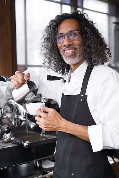 Propietario de negocio sonriente de tiro medio haciendo café