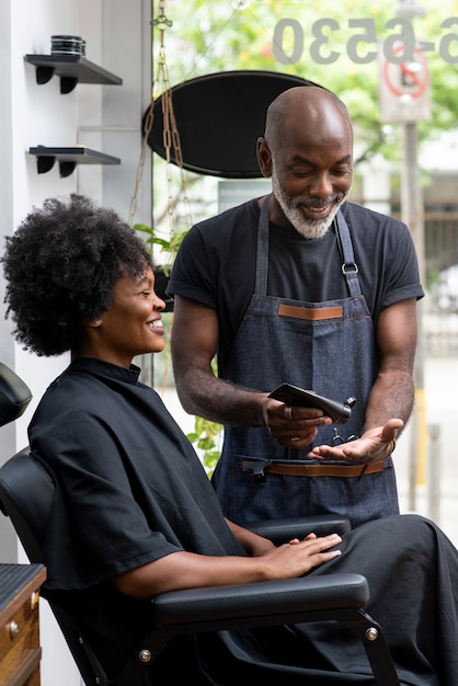 Foto gratuita propietario de peluquería latina cuidando a un cliente