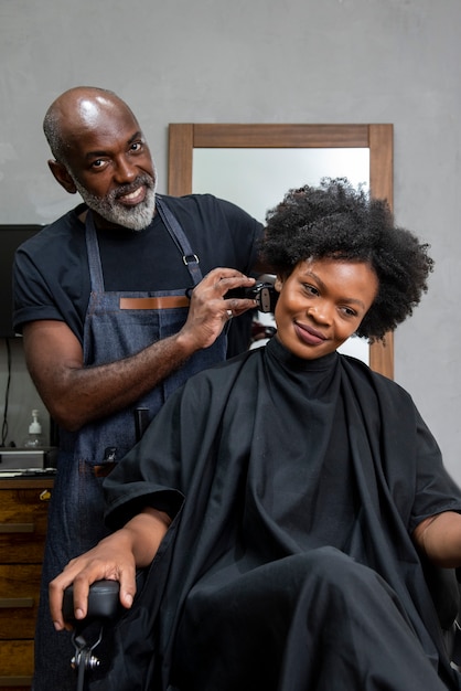 Foto gratuita propietario de peluquería latina cuidando a un cliente