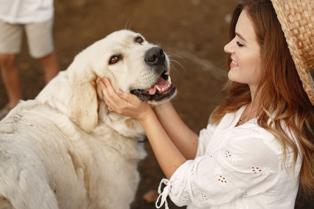 Propietario y perro labrador retriever en un patio. Mujer con un vestido blanco. Perro perdiguero de oro