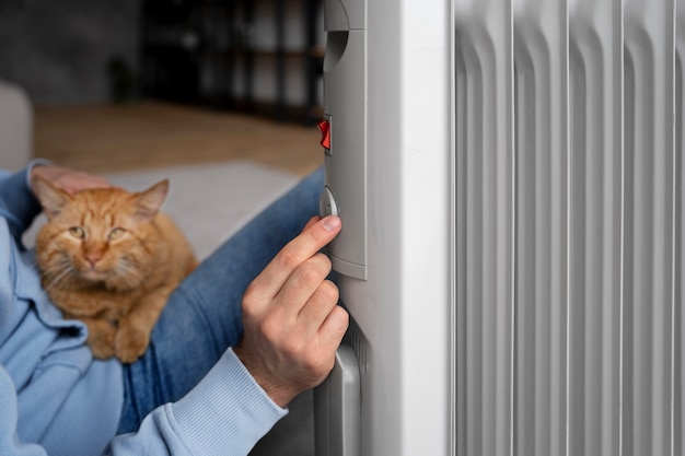 Foto gratuita propietario sosteniendo gato y subiendo el calor