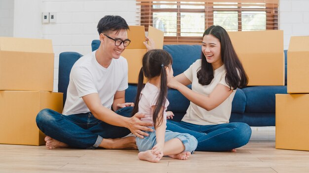 Propietarios de la familia joven asiática feliz en casa nueva