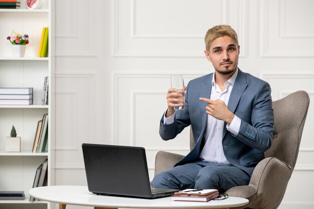 Psicólogo lindo apuesto joven profesional ejecutando sesiones en línea con un vaso de agua