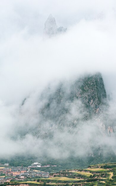 Pueblo y montaña rocosa cubierta de niebla