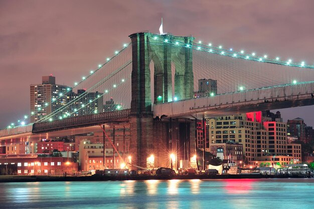 Puente de Brooklyn sobre el East River en la noche en la ciudad de Nueva York Manhattan con luces y reflejos.