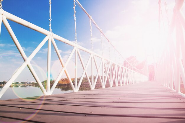 Puente de cuerda con reflejo de la puesta de sol y cielo azul