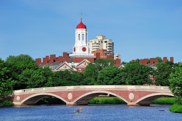 Foto gratuita puente john w. weeks y torre del reloj sobre el río charles en el campus de la universidad de harvard en boston con árboles, barcos y cielo azul.