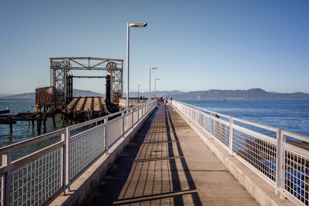 Puente de madera marrón sobre el mar azul bajo un cielo azul durante el día