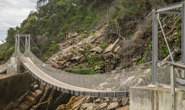 Puente de madera y metal que rodea la montaña.