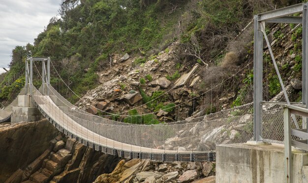 Puente de madera y metal que rodea la montaña.