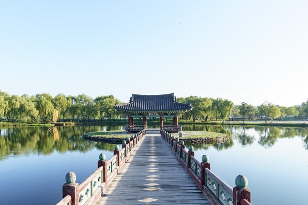 Puente que va sobre un lago hasta un edificio tradicional rodeado por un bosque en Corea del Sur