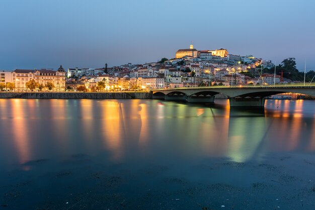 Puente sobre el mar rodeado por Coimbra con las luces que se reflejan en el agua en Portugal