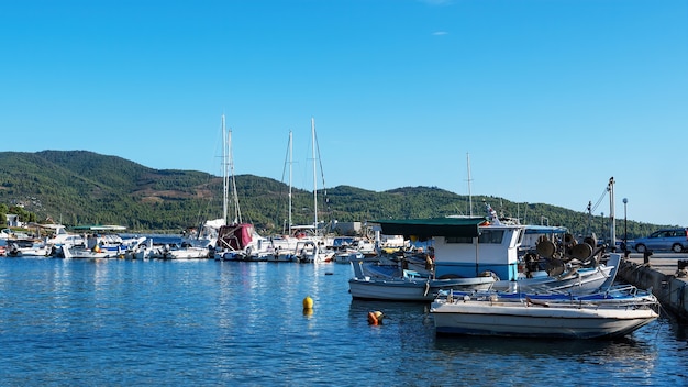 Puerto del mar Egeo con varios yates y barcos amarrados, tiempo claro en Neos Marmaras, Grecia