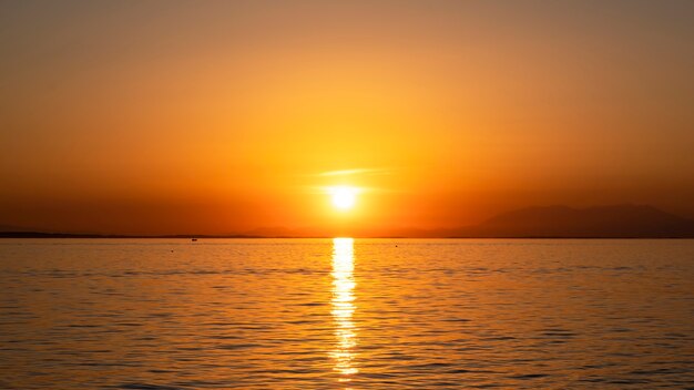 Puesta de sol en la costa del mar Egeo, barco y tierra en la distancia, agua, Grecia