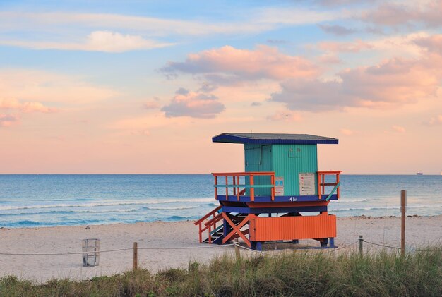 Puesta de sol en Miami South Beach con torre de salvavidas y costa con nubes coloridas y cielo azul.