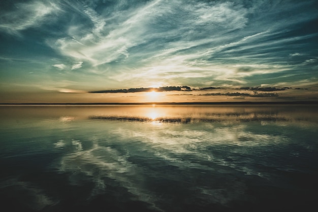 Puesta de sol y las nubes del cielo reflejadas en el océano debajo