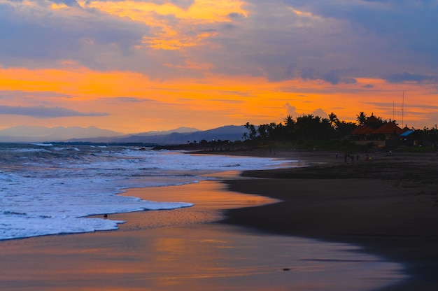 Puesta de sol en el océano, colores brillantes de puesta de sol, reflejo en el agua, palmeras y montañas en el horizonte. Fondo natural.