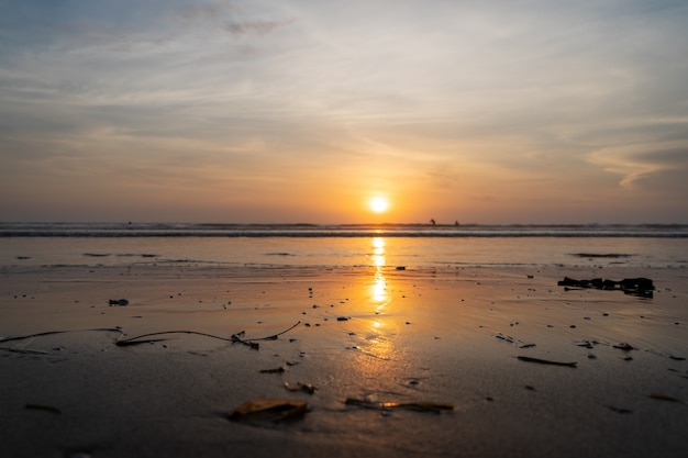 Puesta de sol sobre un mar con olas rompiendo en la playa