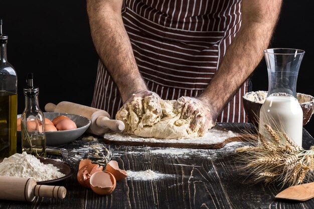 Un puñado de harina con huevo en una cocina rústica. En el contexto de las manos de los hombres amasar la masa. Ingredientes para cocinar productos de harina o pan de masa, magdalenas, pasteles, masa de pizza. copia espacio