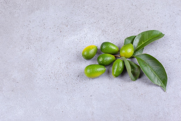 Puñado de kumquats y hojas sobre fondo de mármol.