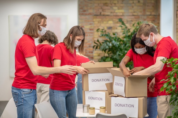 Punto de clasificación. Jóvenes voluntarios con camisetas rojas en el trabajo en un punto de distribución