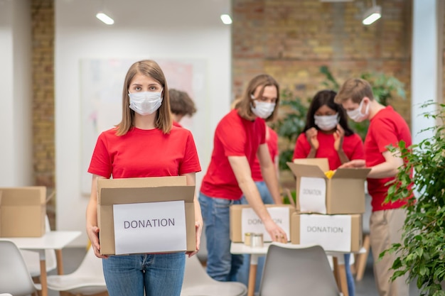 Foto gratuita punto de clasificación. voluntarios en mascarillas faciales trabajando con clasificación de donaciones